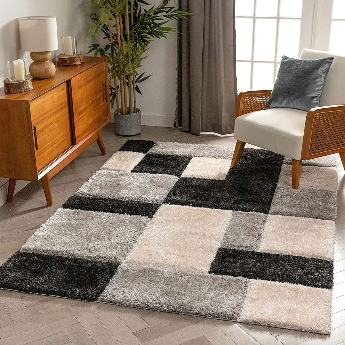 A living room setting with a modern checkered black and white rug on the floor, under a wooden side table and a armchair with a blue cushion - RugNoor