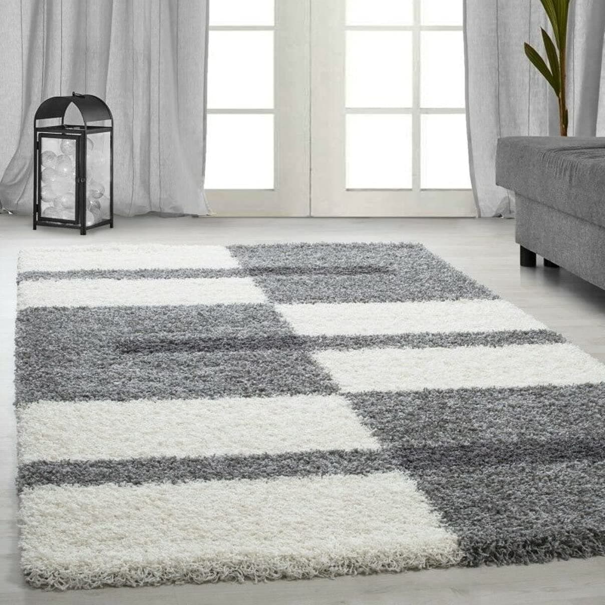 RugNoor's white and grey microfiber shaggy rug with a block pattern laid out on a floor in a living room setting.