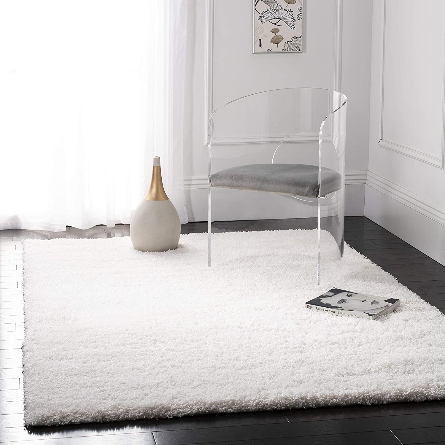 A white microfiber shaggy rug on a dark floor, with a clear chair and a decorative item on the rug for ambiance - RugNoor