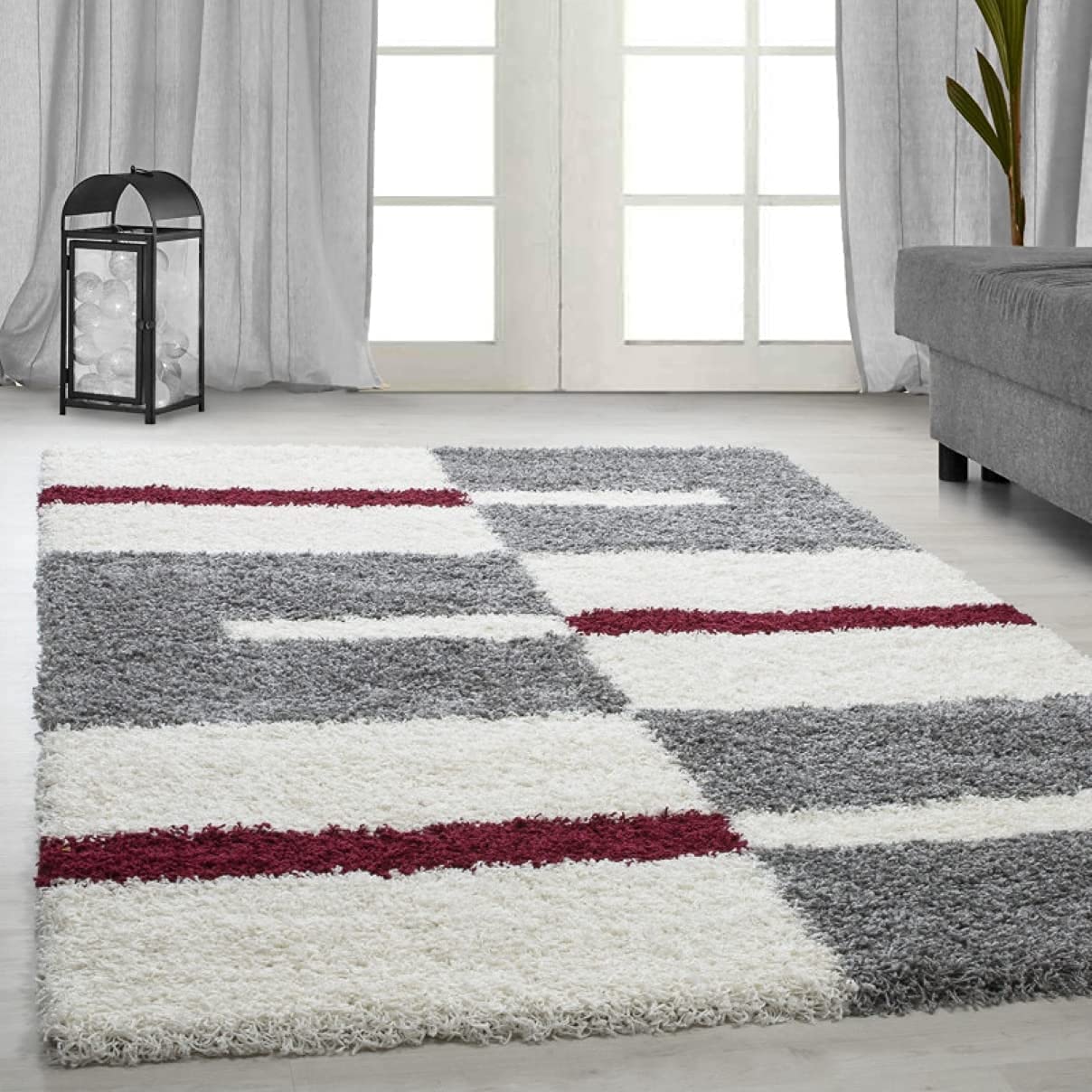 RugNoor's white, red, and grey geometric pattern microfiber shaggy rug on a floor, with a window and a plant in the background.